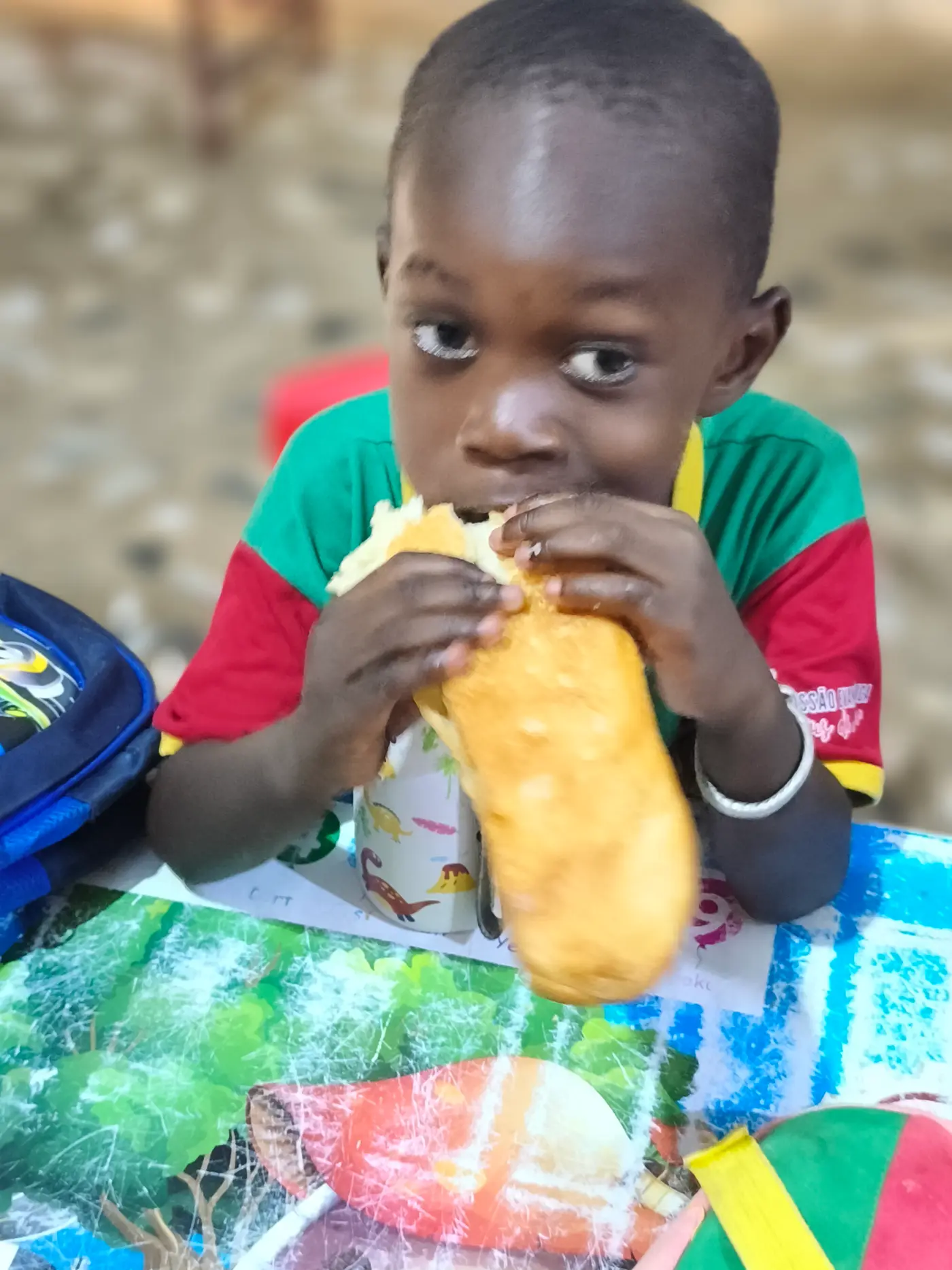 Menino comendo um pão com as duas mãos, de perto
